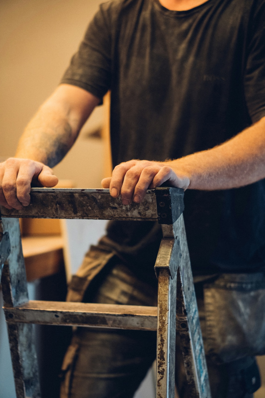 A tradesman's hands gripping a well-used ladder, ready to work